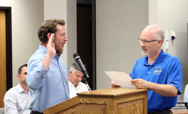 In front from left, Scott Beyer is sworn in Monday, July 23, as Howard's new trustee for Wards 9-10 by Administrative Services Director Chris Haltom.