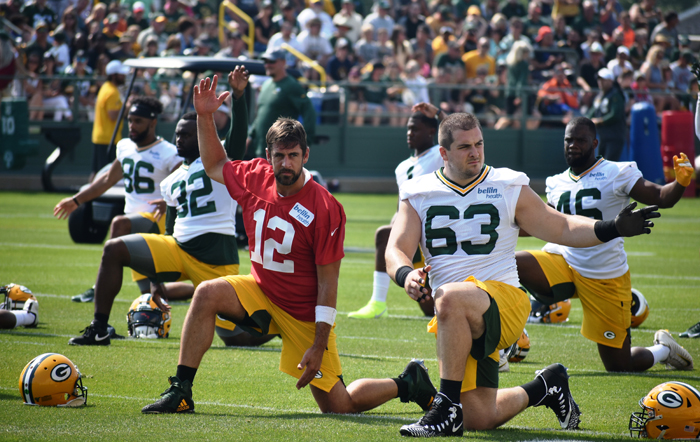 Aaron Rodgers (12) and Corey Linsley (63) stretch.