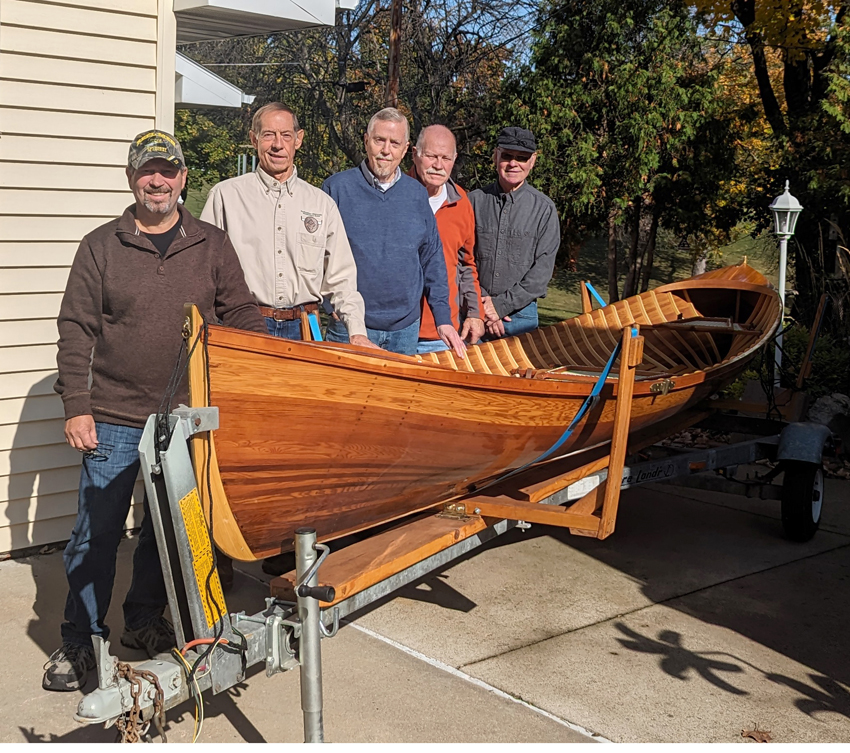 Five members posing next to a canoe