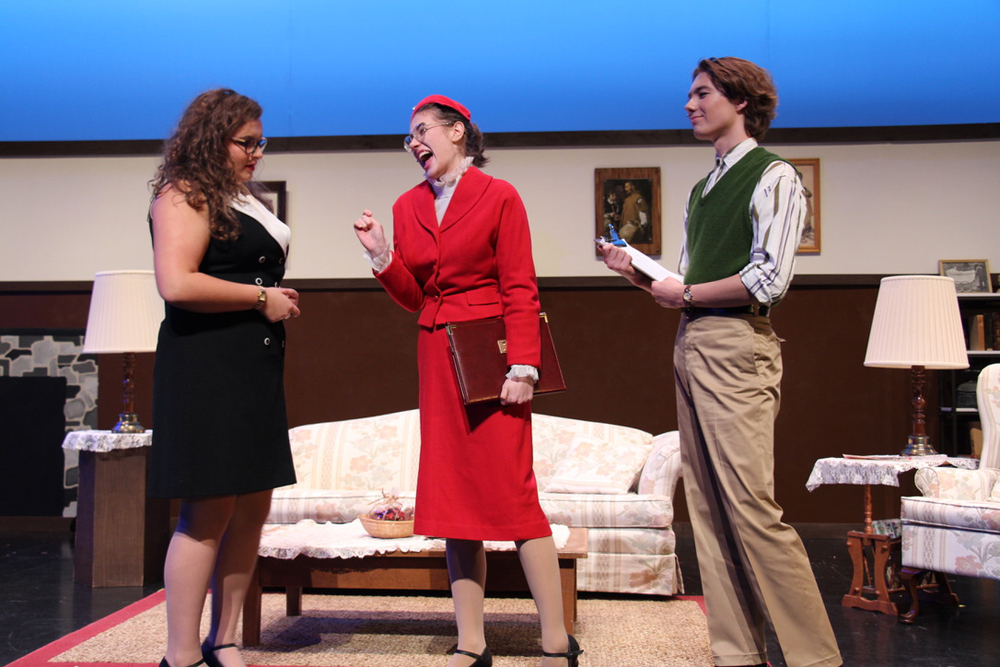 Three students on stage acting in a play