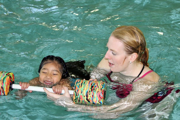 An instructor teaching a child how to swim
