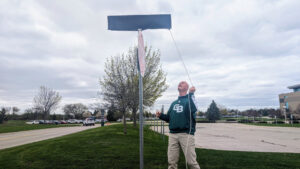 Kevin Borseth pulls the string to unveil the new campus street sign bearing his name in honor of his legacy with Green Bay Phoenix athletics.